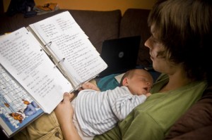 Junger Vater mit Baby auf dem Bauch am Lernen