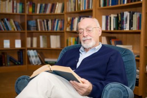 älterer Mann liest ein Buch und bildet sich weiter